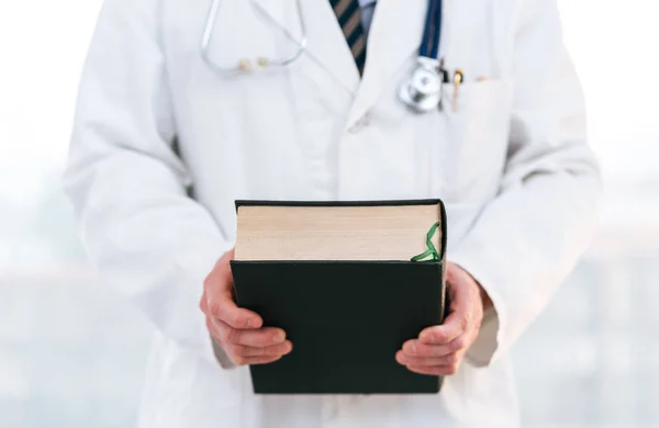 Doktor bir tıp ders kitabı tutan — Stok fotoğraf
