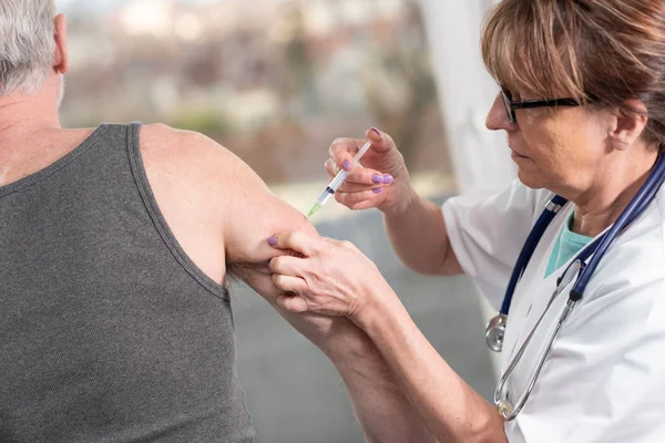 Médica fêmea a injectar vacina no doente sénior — Fotografia de Stock