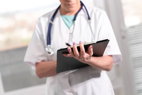 Женщина-врач делает заметки на планшете — стоковое фото