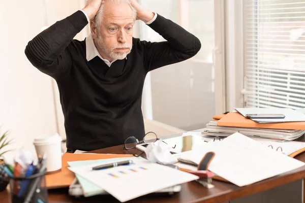 Uomo d'affari sovraccarico seduto a una scrivania disordinata — Foto Stock