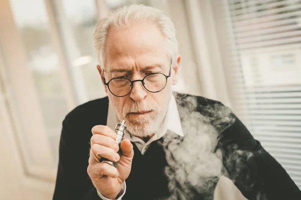 Uomo anziano fumare sigaretta elettronica — Foto Stock