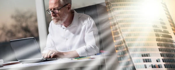 Uomo d'affari anziano che lavora su computer portatile in ufficio, luce dura; adulto — Foto Stock