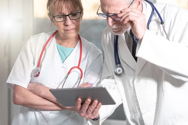 Dois médicos discutindo sobre o relatório médico no tablet — Fotografia de Stock