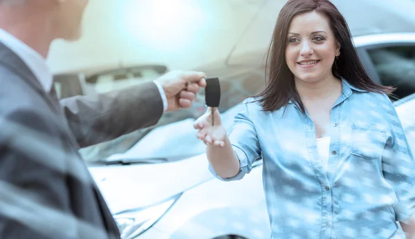 Carro vendedor entregando chaves do carro para a jovem mulher, efeito de luz — Fotografia de Stock