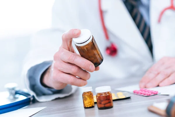 Doctor looking at a bottle of pills — Stock Photo, Image