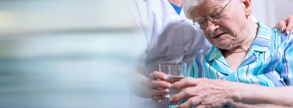 Nurse giving glass of water to senior woman; panoramic banner — Stock Photo, Image