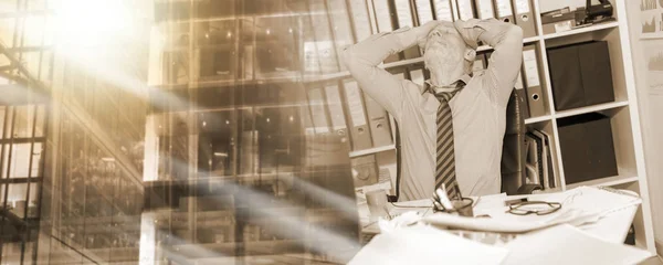 Överarbetade affärsman sitter vid ett rörigt skrivbord, ljuseffekt; Mu — Stockfoto