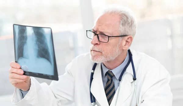 Senior Doctor kijkend naar x-ray — Stockfoto
