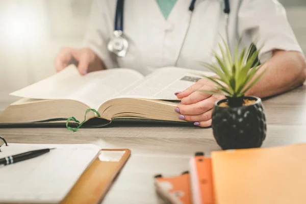 Female doctor reading a textbook — Stock Photo, Image