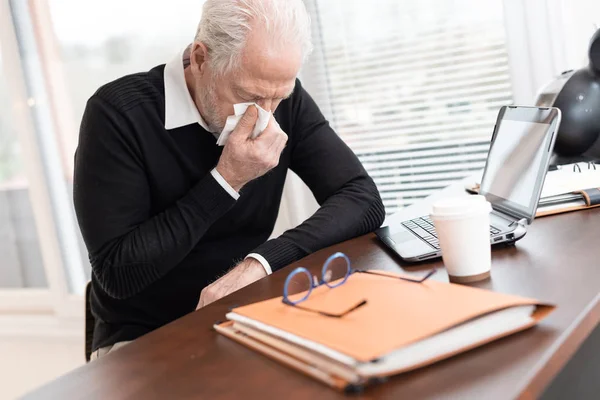 Senior affärsman blåser näsan — Stockfoto