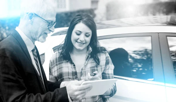 Sprzedawca samochodów dając wyjaśnienia na tablet do młodej kobiety; Wielu — Zdjęcie stockowe