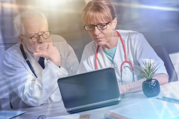 两位医生在笔记本电脑上讨论医疗报告;多个 — 图库照片