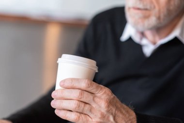 Elinde kağıt kahve fincanı olan işadamı