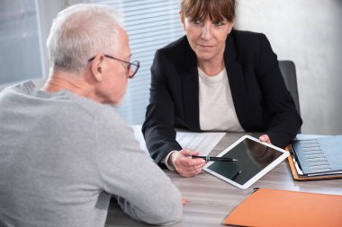 Kadın mali danışman müşterisine dijital tablet hakkında bilgi veriyor