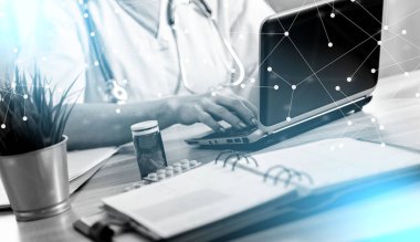 Tıp ofisinde dizüstü bilgisayar kullanan kadın doktor.