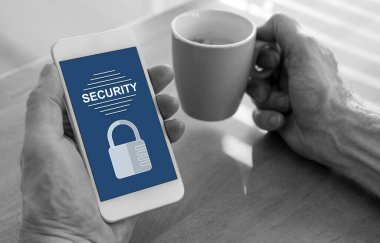 Erkek eller, güvenlik konsepti ve bir fincan kahve olan akıllı bir telefonu tutuyor.