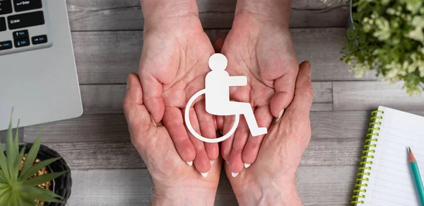 Concept of disability insurance with paper disabled person in hands