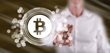 Bir adam dokunmatik ekranda bitcoin konseptine parmağıyla dokunuyor.