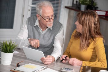 Ofiste dijital tablet üzerinde çalışan iki olgun iş arkadaşı
