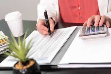 İş kadını hesap makinesi kullanıyor ve finansal veriler üzerinde çalışıyor