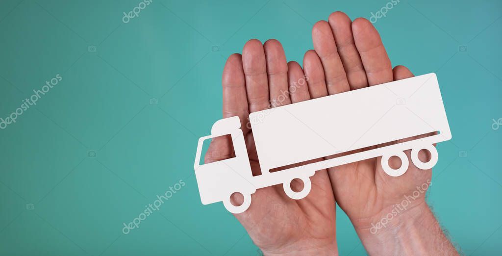Concept of truck insurance with paper truck in hands on turquoise color background