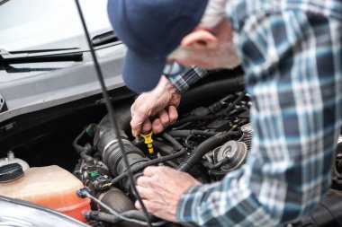 Araba tamircisi bir arabanın motorunu kontrol ediyor.