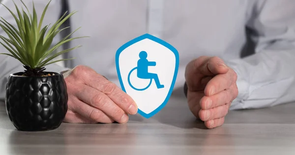 Concept of disability insurance with paper shield protected by hand of insurer