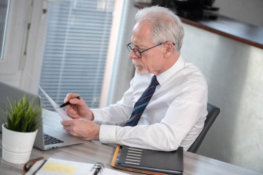 Üst düzey işadamı ofiste belgeyi kontrol ediyor