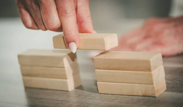 Female hand building a bridge with wooden blocks; concept of association