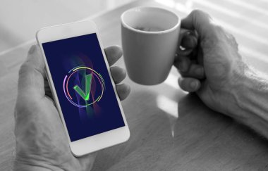 Erkek eli akıllı bir telefon ve bir fincan kahve tutuyor.