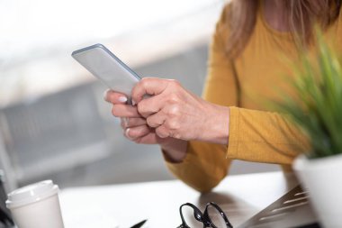 Kadın cep telefonunu tutuyor ve kullanıyor.