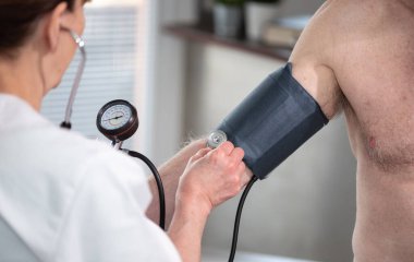 Kadın doktor kan basıncını sfenometre ile ölçüyor.