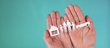 Kağıt aile, araba ve ev sigortalı yaşam, otomobil ve ev kavramı turkuaz renkli arka planda.