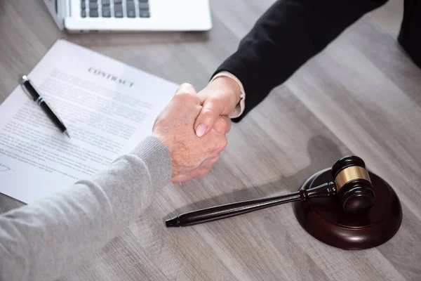 Handshake between female lawyer and male client after signing a contract