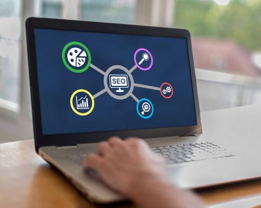 Ekranda seo konsepti olan bir dizüstü bilgisayar kullanan adam