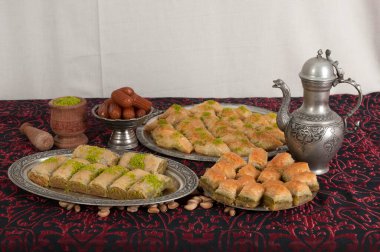 Geleneksel Türk tatlıları masada. Baklava ve tulumba tatlısı. Fıstık, ceviz, hamur ve şeker şerbetinden yapılmış tatlılar. Koyu masa örtüsü ve dekorasyon.