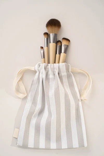 Zero waste concept. Set of eco natural bamboo make up tools in a cotton bag on a white background. Top view, copy space. Eco-friendly, no plastic.