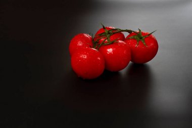 siyah bir arka plan üzerinde dalları üzerinde kırmızı domates