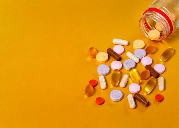 Pills from a jar on a gold background, close-ups of vitamins of different groups, such as vitamins A, B, C, E, D, Lutein + blueberries, Beta-Karatin + Sea-buckthorn, Black thyme oil, gathered,Omega 3.