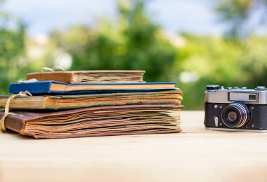 Yaz bahçesinde hafif ahşap bir masada eski fotoğraf albümleri eski kamera.