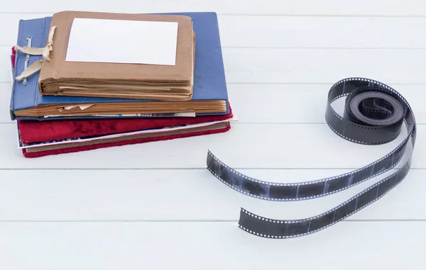 Old photo albums with photographic film on a light wooden table.