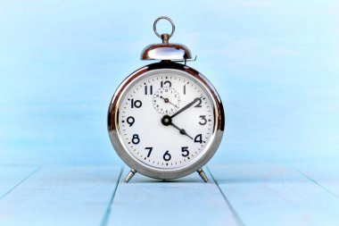  Hafif ahşap bir masa üzerinde Retro çalar saat. Mavi arka plan.