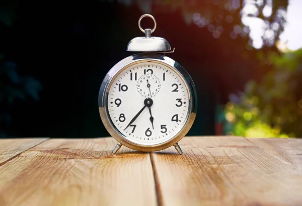 Yaz bahçesinde ahşap bir masada Retro çalar saat.