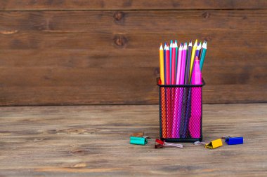 Okula geri dön. Ahşap bir arka plan üzerinde bir organizatör renkli kalemler. Kopyalama alanı.