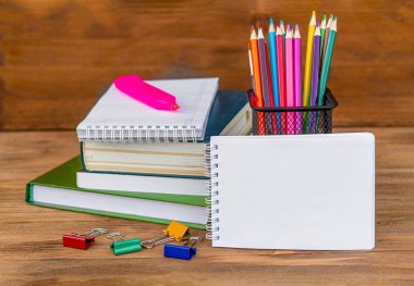 Okula geri dön! Okul malzemeleri, ahşap arka plan da. Çalar saat. Renkli kalemler. Bir yığın kitap. Mockup ücretsiz.