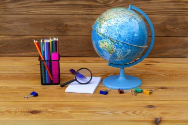 Okula geri dön! Küre, Dünya modeli, Asya ve Avustralya bir dünya üzerinde ahşap bir masa üzerinde eğitim malzemesi. Renkli kalemler, defter ve büyüteç dünya ile çalışmak için.