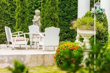 Beyaz masa eros heykeli ve çiçek pot dekorasyon ile rahat ev çiçek bahçesinde yaz ayarla..