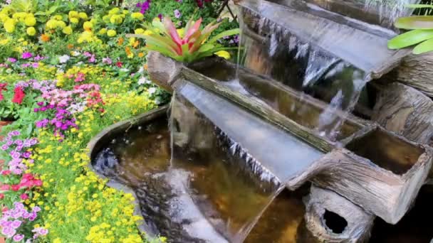 夏の居心地の良いホームフラワーガーデンで映像滝の流れと鮮やかな花のポットの装飾 — ストック動画