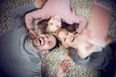 Mutlu genç ailesinin gülümseyen ve selfie yerde yatarken yapma üstten görünüm