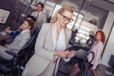 İş kadını ofiste iş arkadaşları önünde tablet kullanma